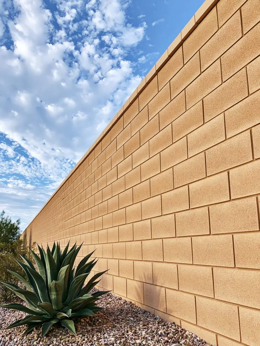 Repaired tan block wall in Tempe, AZ running clean and straight up the property line with a mature agave at the base